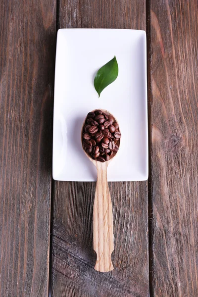 Wooden spoon of coffee beans on tray on wooden background — Stock Photo, Image