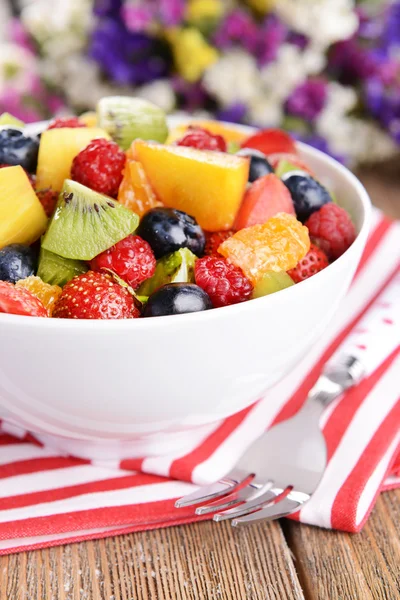 Finom gyümölcssaláta tányérral az asztalon közelkép — Stock Fotó