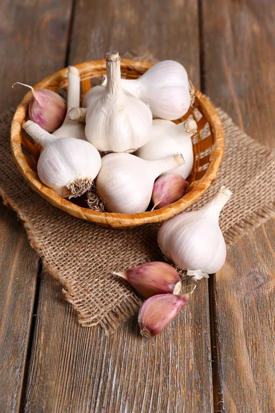 Fresh garlic in wicker basket, on wooden background — Stock Photo, Image