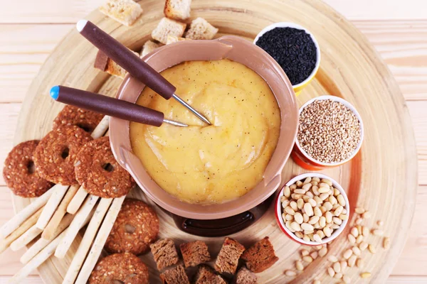 Fondue, biscuits, spices and rusks on bamboo plate on wooden background — Stock Photo, Image