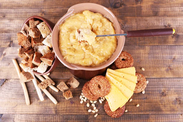 Fondue, tranches de fromage et biscuits sur fond de bois — Photo