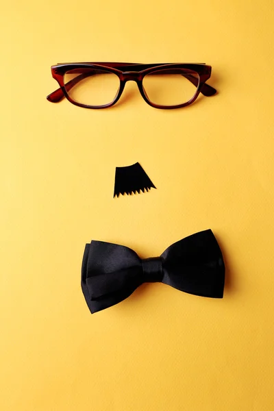 Lunettes, moustache et noeud papillon formant le visage de l'homme sur fond jaune — Photo