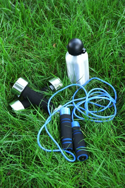 Hanteln und Flasche mit Wasser auf grünem Gras Hintergrund — Stockfoto