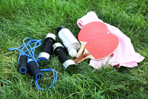 Sortimento de equipamentos esportivos no fundo grama verde — Fotografia de Stock