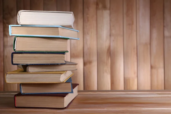 Książki na drewnianym stole na tle ściany drewniane — Zdjęcie stockowe