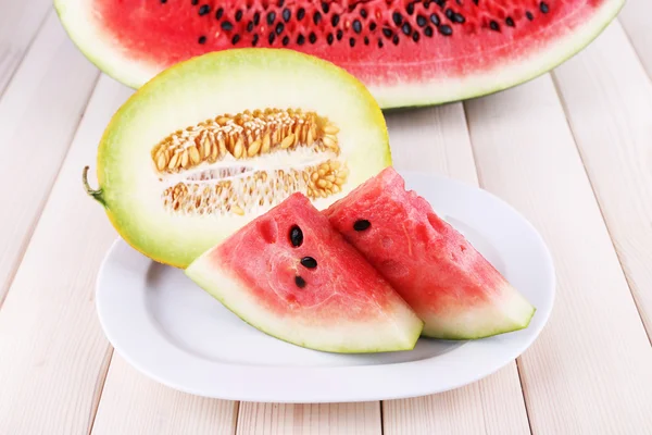 Segmenten van watermeloen op plaat op houten achtergrond — Stockfoto