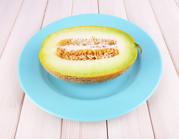 Melon on blue plate on wooden background — Stock Photo, Image