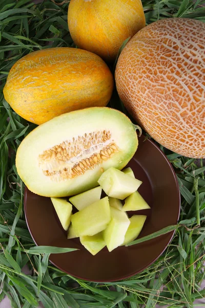 Rodajas de melón sobre plato marrón sobre fondo de hierba fresca —  Fotos de Stock