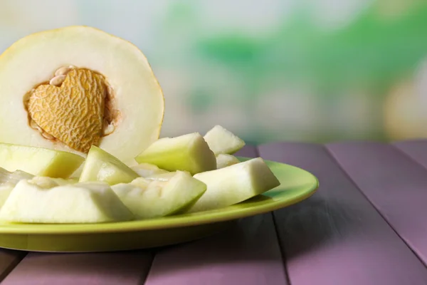 Slice of melon on green plate on wooden table on natural background — Stock Photo, Image