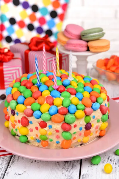Delicioso bolo de arco-íris na placa na mesa no fundo brilhante — Fotografia de Stock