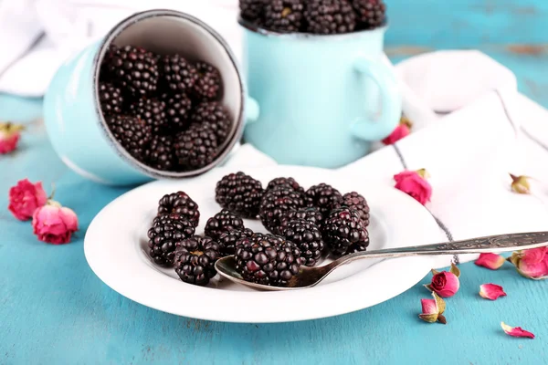 Moras dulces en tazas y en plato, sobre fondo de madera de color — Foto de Stock