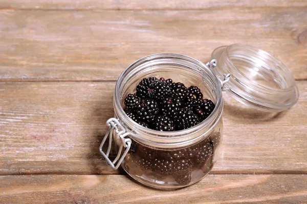 Sweet blackberries in glass jar on wooden background — Stock Photo, Image