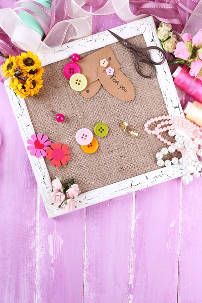 Scrapbooking craft materials and wooden frame with sackcloth inside on color wooden background — Stock Photo, Image