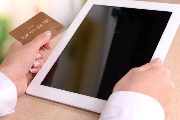 Les mains féminines tenant la carte de crédit et la tablette d'ordinateur sur fond lumineux — Photo