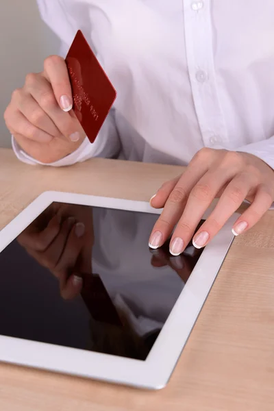 Mãos femininas segurando cartão de crédito e tablet computador na mesa de perto — Fotografia de Stock