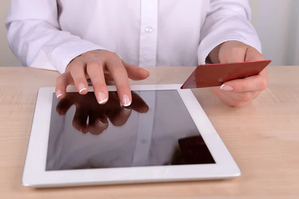 Female hands holding credit card and computer tablet on table close up — Stock Photo, Image