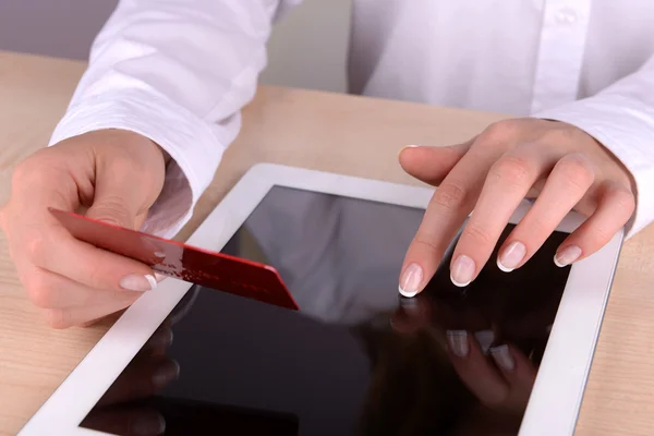 Frauenhände halten Kreditkarte und Computer-Tablet aus nächster Nähe auf dem Tisch — Stockfoto