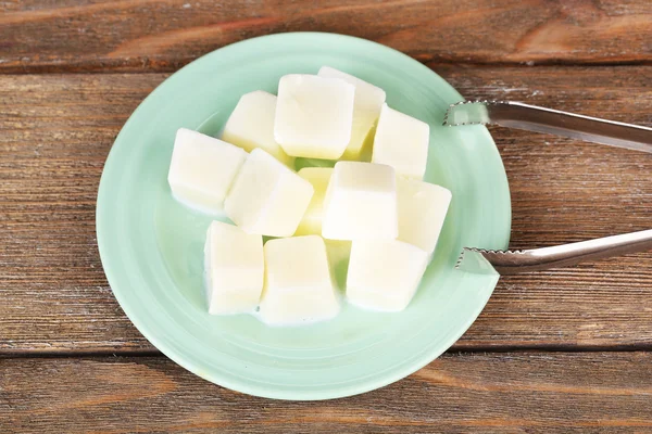 Milcheiswürfel auf Teller auf hölzernem Hintergrund — Stockfoto