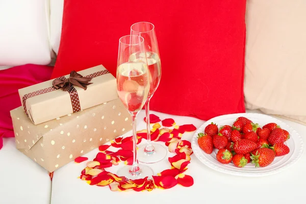 Romantische Stilleven met champagne, aardbei en bloemblaadjes van rozen op sofa — Stockfoto