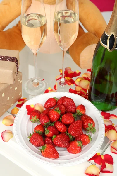 Romantische Stilleven met champagne, aardbei en bloemblaadjes van rozen close-up — Stockfoto