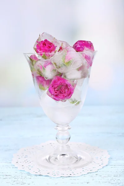 Ice cubes with rose flowers in glass bowl on light background — Stock Photo, Image