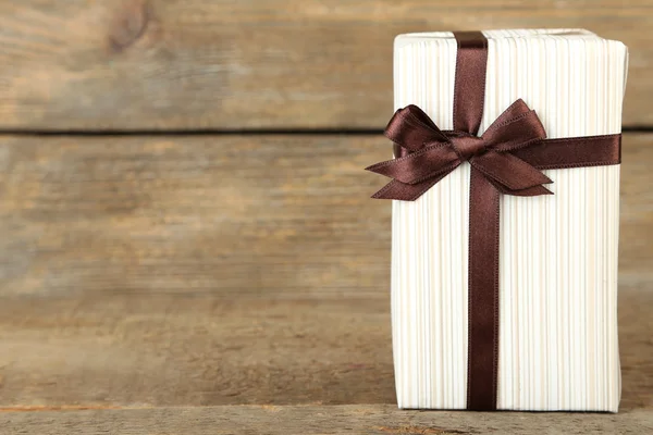 Gift box with colorful ribbon on wooden background — Stock Photo, Image