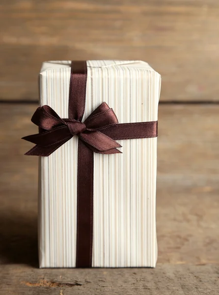Geschenkbox mit buntem Band auf Holzhintergrund — Stockfoto