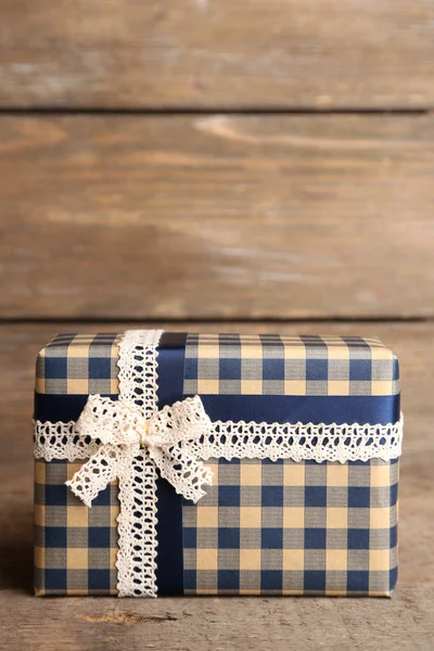 Gift box with colorful ribbon on wooden background — Stock Photo, Image