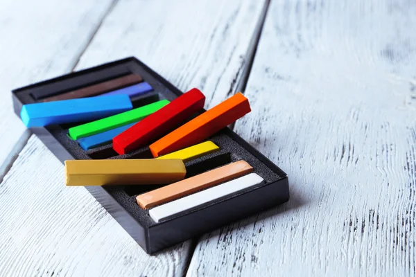 Pasteles de tiza de colores en caja sobre fondo de madera — Foto de Stock