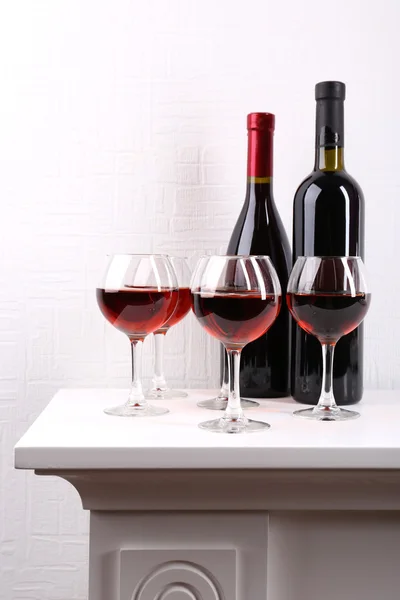 Glasses and wine bottle on table in room — Stock Photo, Image
