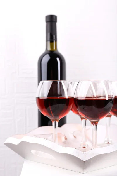 Glasses and wine bottle on tray in room — Stock Photo, Image