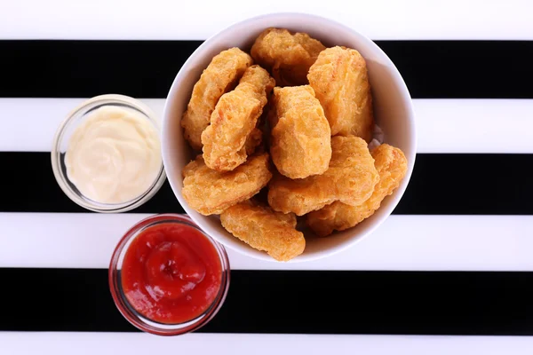 Fried chicken nuggets and sauces on striped background — Stock Photo, Image