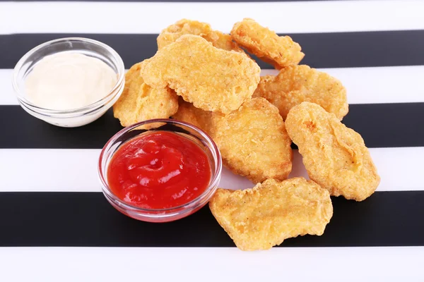Nuggets de pollo frito y salsas sobre fondo rayado —  Fotos de Stock