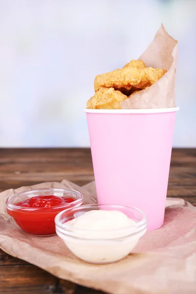 Chicken Nuggets in Tasse mit Soßen auf Tisch auf hellem Hintergrund — Stockfoto