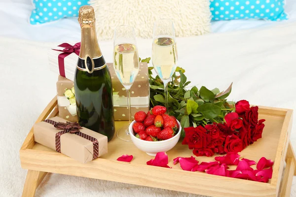 Romantisches Stillleben mit Champagner, Erdbeere und Rosen auf dem Bett — Stockfoto