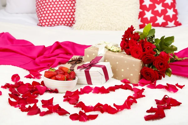 Natura morta romantica con fragola, scatole regalo e petali di rose sul letto — Foto Stock