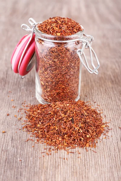 Dried rooibos tea in glass jar on wooden table — Stock Photo, Image