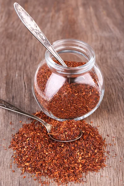 Dried rooibos tea in glass jar on wooden table — Stock Photo, Image