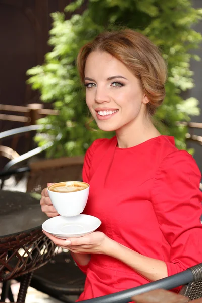 Beautiful young woman sitting in cafe — Stock Photo, Image