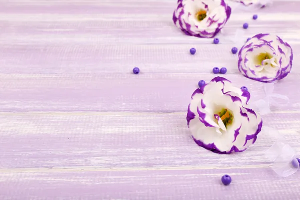 Beautiful artificial eustomas on purple wooden background — Stock Photo, Image