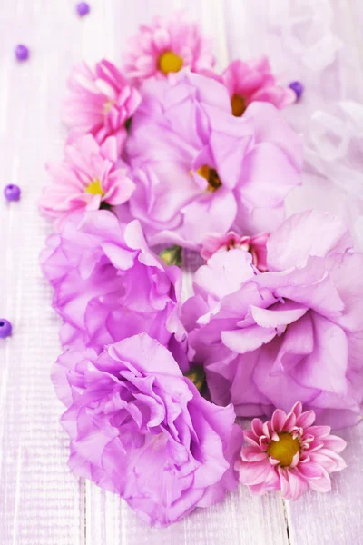 Schöne Chrysanthemen und künstliche Eustoma-Blüten auf violettem Holzhintergrund — Stockfoto