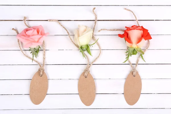 Belles roses et étiquettes vides sur fond blanc en bois — Photo