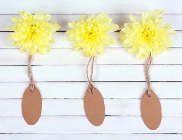 Bellissimi fiori di crisantemo e tag vuoti su sfondo di legno bianco — Foto Stock