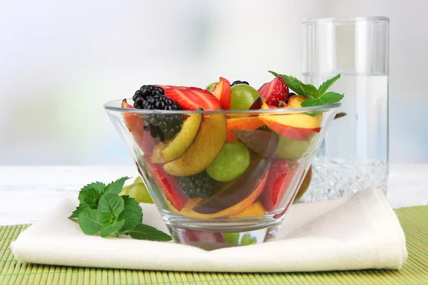 Fresh tasty fruit salad on table, on light background — Stock Photo, Image