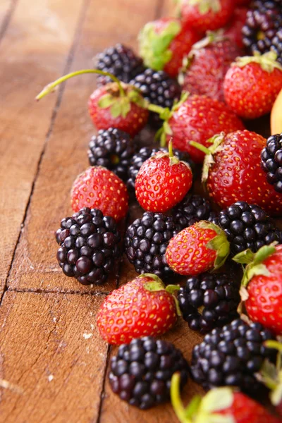 More e fragole su fondo di legno — Foto Stock