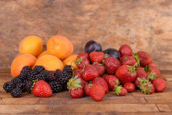 Спелые плоды и ягоды на деревянном фоне — стоковое фото