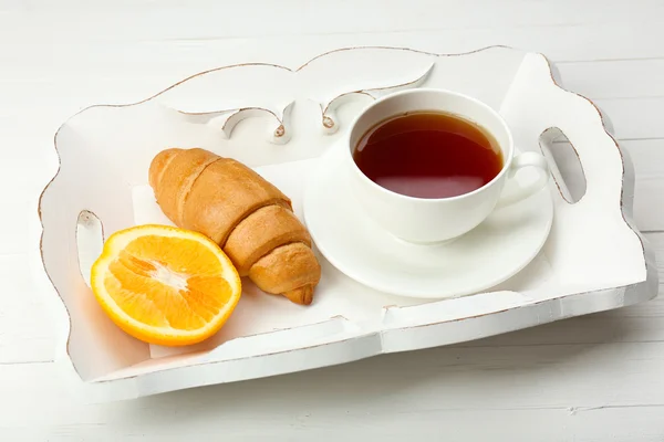 Leckeres Frühstück mit einer Tasse Tee, frischem Croissant und Orange — Stockfoto