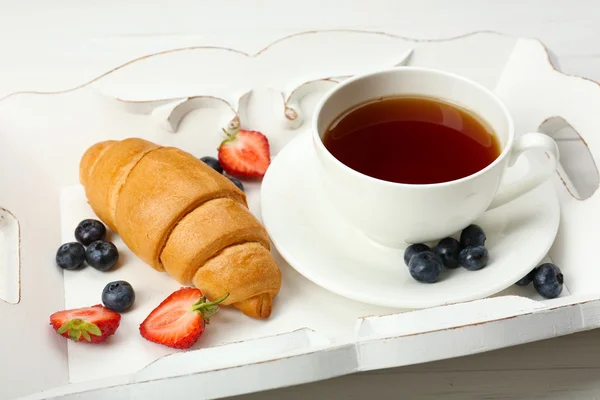 Deliziosa colazione con tazza di tè, croissant fresco e bacche — Foto Stock