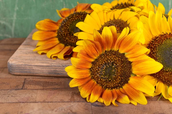 Beautiful sunflowers on table on wooden background — Stock Photo, Image