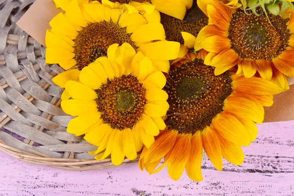 Beautiful sunflowers on wicker stand on table close up — Stock Photo, Image